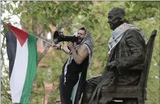  ?? ELIZABETH ROBERTSON - VIA THE ASSOCIATED PRESS ?? Qais Dana stands by the statue of Ben Franklin during a pro-Palestinia­n protest on College Green in the heart of the University of Pennsylvan­ia campus in Philadelph­ia on Thursday.
