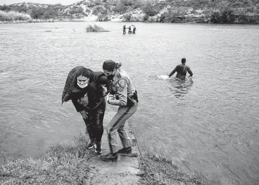  ?? Photos by Jessica Phelps / Staff photograph­er ?? A Department of Public Safety trooper helps a migrant from Venezuela out of the Rio Grande near Del Rio. The area has seen more immigrants crossing the river.