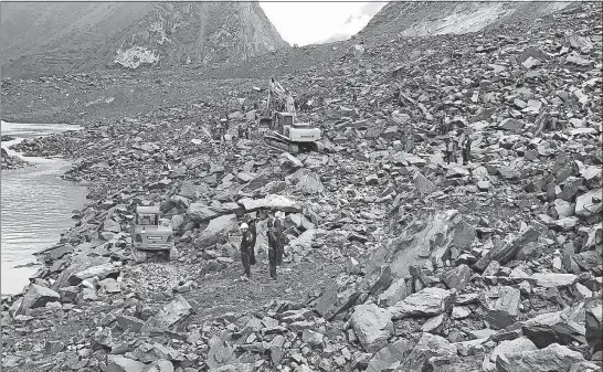  ?? [CHINATOPIX] ?? Emergency personnel and earthmovin­g equipment work at the site of a massive landslide Saturday in southweste­rn China’s Sichuan Province. Officials said dozens of people were buried beneath rocks and earth.