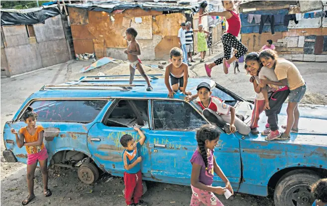  ??  ?? Children play on an abandoned car in one of the shanty towns in Caracas
‘Venezuela is twice the size of Iraq with only a slightly smaller population, and teeters on the verge of chaos. Any invasion requires preparatio­ns on a similar scale’