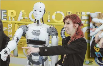  ?? AP PHOTO ?? PRINTED IN PLASTIC: A woman poses beside French designer Gael Langevin’s InMoov robot after it was unveiled yesterday at a tech fair in Bucharest, Romania. Based on an idea derived from a prosthetic hand Langevin made in 2011, the robot can be...