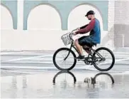  ?? WILFREDO LEE/AP 2018 ?? A cyclist rides through flooded waters in Miami. Tidal flooding will increase in many spots in the U.S., experts say.