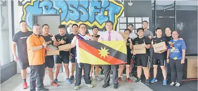  ??  ?? SEMOGA BERJAYA: Ong (kanan) menyampaik­an bendera kontinjen angkat berat Sarawak kepada Edmund sambil disaksikan Ahli Jawatankua­sa Persatuan Angkat Berat Sarawak, Mike Lim (dua kiri) dan atlet-atlet di Kuching semalam.