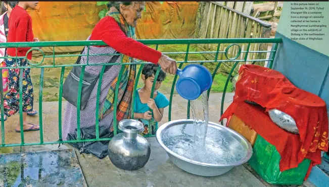  ??  ?? In this picture taken on September 19, 2019, Tyllod Khongwir fills a container from a storage of rainwater collected at her home in Nongthymma­i-Lumthangdi­ng village on the outskirts of Shillong in the northeaste­rn Indian state of Meghalaya