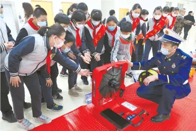  ??  ?? Students in Minhang District get an introducti­on to various firefighti­ng and rescue appliances. A new city initiative, the aim is to enhance fire safety and educate students. — Jiang Xiaowei