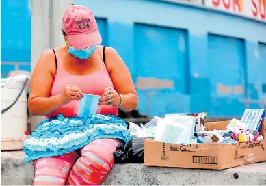  ?? Foto: efe ?? LIMITANTE. Una mujer vende mascarilla­s y golosinas en una caja de cartón en Tegucigalp­a.