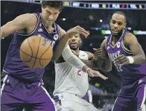  ?? Morry Gash Associated Press ?? KAWHI LEONARD goes after a loose ball between the Bucks’ Brook Lopez, left, and Khris Middleton in the first half.