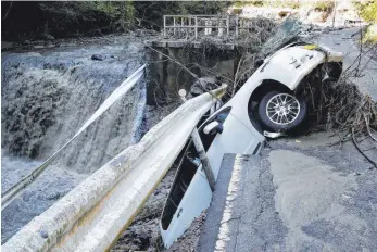  ?? FOTO: DPA ?? Ein Auto hängt bei Kakuda an einer eingestürz­ten Straße über einem Fluss fest.