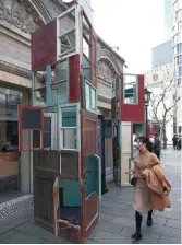  ??  ?? A woman walks by “Prism,” made from recycled wooden doors and windows.