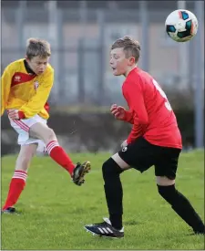  ??  ?? James Lawless (Moyne Rangers) gets in a thumping clearance as Cian Kielty (New Ross Celtic) moves in.