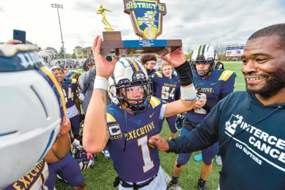  ?? APRIL GAMIZ/THE MORNING CALL ?? Executive Education Academy quarterbac­k Darmel Lopez and head coach Larry Ford, right, celebrate the Raptors’ first District 11 Class 2A title on Saturday, a 32-29 victory over Catasauqua.