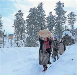  ?? AFP ?? Villagers carry rice after heavy snowfall in Budgam district of Srinagar on January 18.