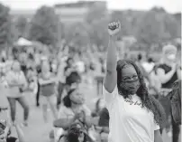  ??  ?? A women raises her fist as she watches a speaker during a Juneteenth celebratio­n in Tulsa on Friday. [BRYAN TERRY/THE OKLAHOMAN]