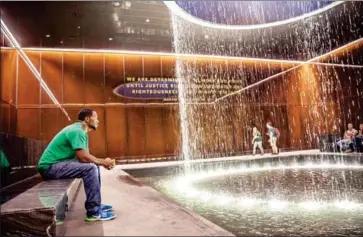  ?? EVELYN HOCKSTEIN/THE WASHINGTON POST ?? Dwayne Wilson of Delaware, who was on his first visit to the National Museum of African American History and Culture, sits in the Contemplat­ive Court. The room, which features an indoor water cascade, has become a favourite spot in the museum for many.