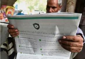  ??  ?? An Indian newspaper vendor reading a newspaper with a full back page advertisem­ent from WhatsApp intended to counter fake informatio­n. — AFP