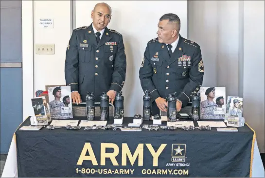  ?? [IAN C. BATES /NEW YORK TIMES] ?? Army recruiters Sgt. Dira An, left, and Sgt. Julio Diaz man a table at a job fair in Seattle. To work in cities that don’t typically have a lot of recruits, they frame enlistment as something that is both a public service and an adventure that promises travel.