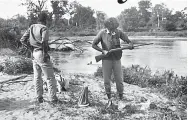 ??  ?? Breaking amp on the banks of the Mahaweli (5th day). The writer is seen (at right) examining the rifle