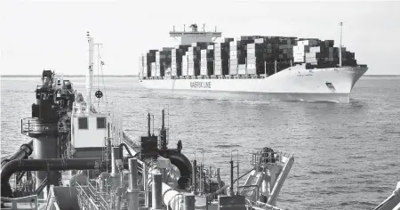  ?? STEPHEN M KATZ/STAFF FILE ?? A container ship passes a dredge working on Virginia’s harbor widening in December.