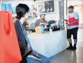  ?? Christina House For The Times ?? RICKY SIERRA, left, and Fernando Godoy of DoorDash wait to pick up orders at Mendocino Farms in El Segundo as Danny Dumas works the takeout area.
