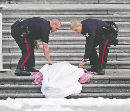  ?? LARRY WONG ?? Edmonton police officers cover up a body found on the front steps of the Alberta Legislatur­e Monday.