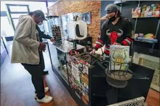  ?? KEITH SRAKOCIC - THE ASSOCIATED PRESS ?? Shop owner Gian Oliver, right, waits on customers at the Glassworks Gallery on Pittsburgh’s Southside as counties in southweste­rn Pennsylvan­ia join northweste­rn and the north central regions with more relaxed COVID-19 prevention restrictio­ns, Friday, May 15, in Pittsburgh. It was the first day the store had been open to walk in customers to purchase items there since it closed in March.