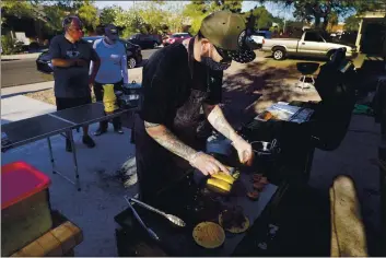  ?? PHOTOS BY ROSS D. FRANKLIN — THE ASSOCIATED PRESS ?? Chef Mike Winneker prepares tacos in front of his home on April 3, in Scottsdale, Ariz. Beaten down by the pandemic, many laid-off or idle restaurant workers have pivoted to dishing out food with a taste of home. Some have found their entreprene­urial side, slinging their culinary creations from their own kitchens.