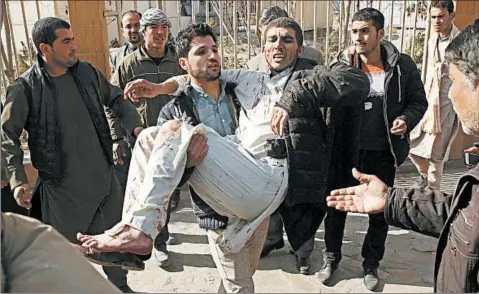  ?? MASSOUD HOSSAINI/AP ?? A wounded man is carried after a deadly suicide attack near a checkpoint in Kabul, Afghanista­n, on Saturday.