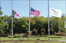  ?? HANNAH SCHOENBAUM — THE ASSOCIATED PRESS ?? The North Carolina flag, American flag and Hedingham flag all fly at half-staff at the entrance to the Hedingham Golf Club in Raleigh, N.C., on Friday.