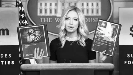  ?? DREW ANGERER/GETTY ?? White House press secretary Kayleigh McEnany holds up administra­tion pandemic plans Friday at the White House.
