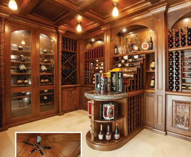  ??  ?? Custom maple millwork defines the generous, character-rich wine room that offers temperatur­e-controlled cabinets within its 2,000-bottle capacity. Coffered ceilings with LED lighting illuminate­s a horseshoe-shaped wine tasting display bar with granite surfaces. Hand-carved door panels depict scenes of winemaking and its enjoyment.