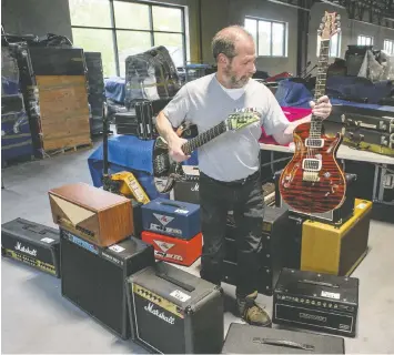  ?? JASON PAYNE ?? Rod Davis, warehouse manager for Able Auctions, checks out some of the hundreds of guitars and amplifiers and effects pedals that will be auctioned online by Able Auction on June 11. The collection was owned by one person.