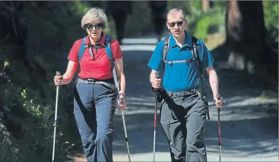  ?? POOL / REUTERS ?? La primera ministra británica, Theresa May, camina junto a su marido, Philip, por un bosque de los Alpes suizos al principio de sus vacaciones