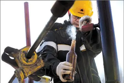  ?? Bloomberg News/ANDREY RUDAKOV ?? A worker collects a crude oil sample at a well operated by Rosneft in the Samotlor oilfield near Nizhnevart­osk, Russia, on March 20. Russia joined OPEC in a January deal to cut output and strengthen prices.