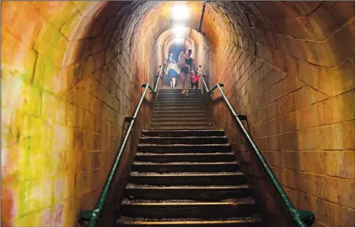  ?? (AP/Tony Hicks) ?? People walk down the steps of Smugglers Tunnel that lead to Ness Cove beach July 22 in Shaldon, Devon, England.