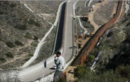  ?? MOISES CASTILLO — THE ASSOCIATED PRESS ?? A man looks out at the U.S. border where workers are replacing parts of the U.S. border wall for a higher one, in Tijuana, Mexico, Wednesday. Workers are reinforcin­g and changing pieces of the wall where migrants seeking to reach the U.S. have been crossing.