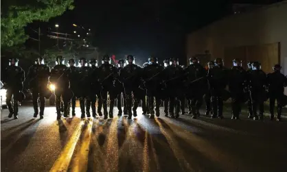  ?? Photograph: Nathan Howard/AP ?? Portland police officers walk through the Laurelhurs­t neighborho­od after dispersing a protest of about 200 people from in front of the Multnomah county sheriff’s office early Saturday.