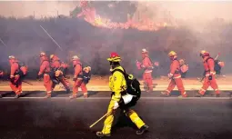  ?? (EPA) ?? ALL IN A DAY’S WORK – Firefighte­rs and inmate volunteers try to contain the fire near the Ronald Reagan Library as the Easy Fire spreads near Simi Valley, north of Los Angeles, California.