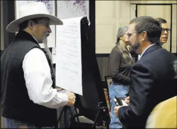  ?? Scott Sonner The Associated Press ?? John Ruhs, left, acting deputy director of the U.S. Bureau of Land Management, talks to Patrick Donnelly, Nevada state director for the Center for Biological Diversity, during a public meeting Wednesday in Sparks.