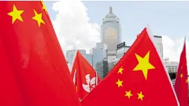  ?? —REUTERS ?? SEEING RED Buildings rise in the background as Hong Kong and Chinese flags are carried by supporters of the national security law on Tuesday.
