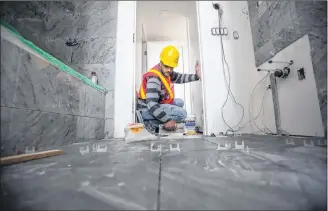 ?? CP PHOTO ?? Hasan Alsheblak, a Syrian refugee who started a floor tiling business in Canada, works at a condo tower under constructi­on in Richmond, B.C. Alsheblak arrived in Canada via Jordan in December 2016 a few years after a missile destroyed his house in Syria.