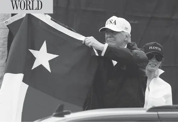  ?? EVAN VUCCI / THE ASSOCIATED PRESS ?? President Donald Trump, with first lady Melania, holds up a Texas flag after meeting supporters in Corpus Christi on Tuesday. his first visit to the state since the storm hit.