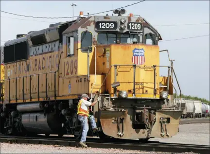  ?? NATI HARNIK — THE ASSOCIATED PRESS FILE ?? A Union Pacific employee climbs on board a locomotive in a rail yard in Council Bluffs, Iowa. This year’s scheduled completion of a $15 billion automatic railroad braking system will bolster the industry’s argument for eliminatin­g one of the two crew members in most locomotive­s. But labor groups argue that single-person crews would make trains more accident prone.