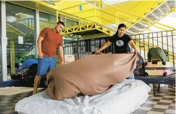  ?? ARMANDO L. SANCHEZ/CHICAGO TRIBUNE PHOTOS ?? Carlos Ramirez and his wife, Betzabeth Bracho, make their bed before sleeping in the lobby of the 5th District police station in Chicago on Wednesday. The two traveled from Venezuela seeking asylum and have been staying at the police station since arriving in Chicago in May.