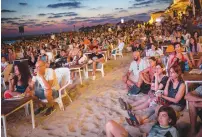  ?? (Miriam Alster/Flash90) ?? PEOPLE WATCH a movie screened as part of the DocAviv film festival, at the Hilton beach in Tel Aviv, last week.