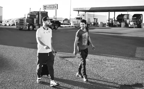  ??  ?? Gevr, right, a truck driver in training, and Butrus, left, his truck driving mentor, unpack their belongings as they stop for the night at the Flying J truck stop in Laredo, Texas. — WPBloomber­g photos