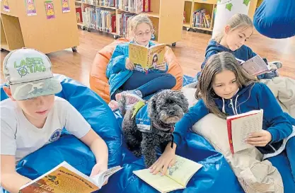  ?? ?? Hora de lectura. Gracie, la perrita negra que llegó desde Holanda, divirtiénd­ose con los más chicos.