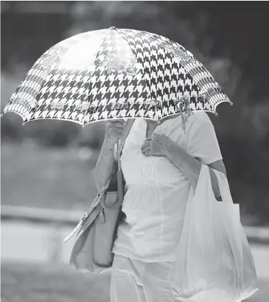  ?? ALLEN MCINNIS / POSTMEDIA NEWS ?? A woman protects herself from the sun. Climate change is listed as one of the biggest threats to mental health.