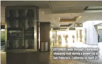  ?? REUTERS ?? CUSTOMERS walk through a darkened shopping mall during a power cut in San Francisco, California on April 21.