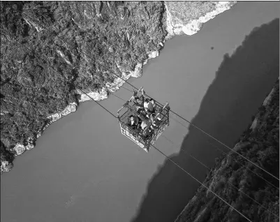  ?? ZHANG ZHI / FOR CHINA DAILY ?? Residents use an aerial cable bridge to cross the Jinsha River, a major tributary of the Yangtze River, in Butuo county, Sichuan province, on Friday. This is the last cable bridge in use across the river. A new bridge is expected to be put into use...