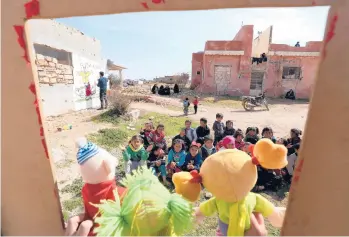  ?? OMAR HAJ KADOUR/GETTY-AFP ?? A day for the kids: Syrian children watch a puppet show Tuesday performed by a local theater group amid the ruins of buildings destroyed during Syria’s civil war in al-Fua, in the northweste­rn Idlib province. Dozens of nations pledged $6.4 billion in aid Tuesday to help tackle war-ravaged Syria’s deepening humanitari­an and economic crises.